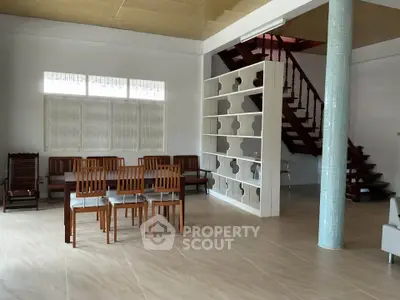 Spacious open-plan living area with modern staircase and elegant dining set