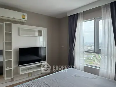 Modern bedroom with large window offering stunning city view, featuring sleek TV setup and air conditioning.