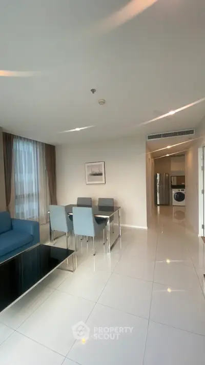 Modern living room with dining area and washing machine in sleek apartment.