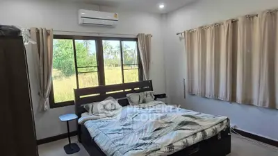 Spacious bedroom with large window and scenic view, featuring modern furnishings and air conditioning.
