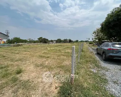 Expansive vacant land with potential for development, featuring clear skies and accessible road.