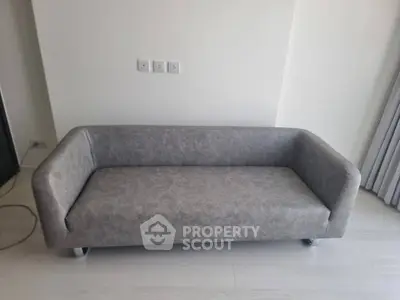 Modern minimalist gray sofa in a bright living room with neutral decor