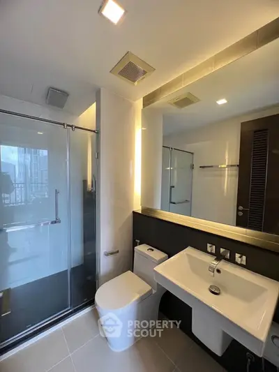 Modern bathroom with glass shower and sleek fixtures in luxury apartment.
