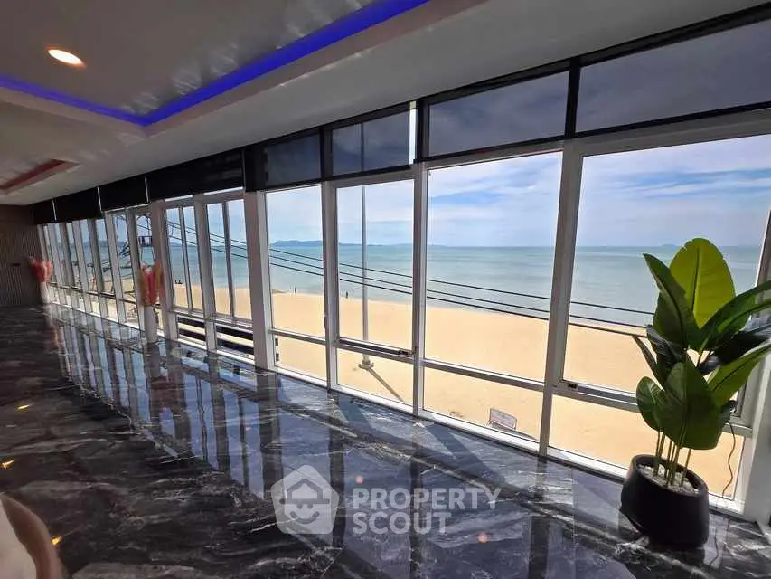 Stunning beachfront view from modern interior with floor-to-ceiling windows.