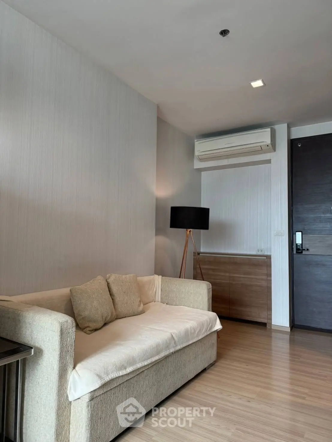 Modern living room with cozy sofa and stylish floor lamp, featuring sleek wooden flooring and air conditioning.