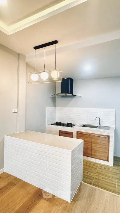 Modern kitchen with sleek design and gas stove, featuring stylish lighting and wooden accents.