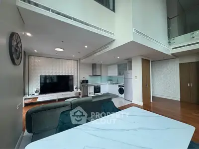 Luxurious modern living room with open kitchen, featuring high ceilings and elegant decor.