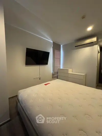 Modern bedroom with wall-mounted TV and air conditioning in a stylish apartment.