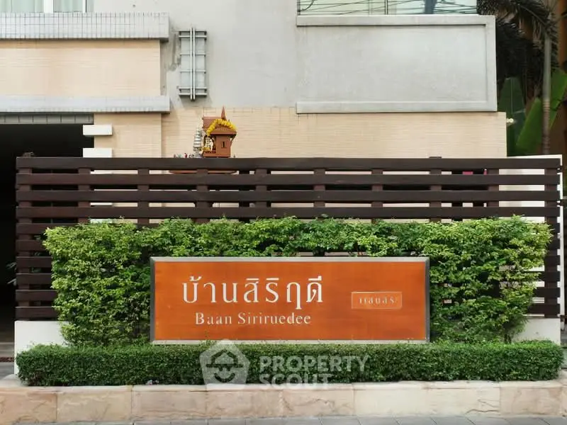 Elegant entrance sign of Baan Siriruedee with lush greenery and modern design.