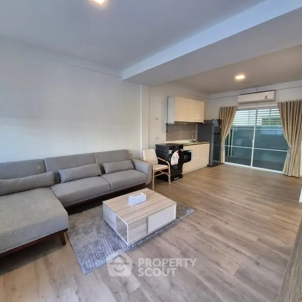 Spacious open-plan living room with modern kitchen and balcony access