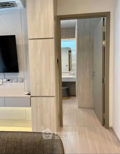 Modern interior with open door leading to a stylish bathroom, featuring sleek design and neutral tones.
