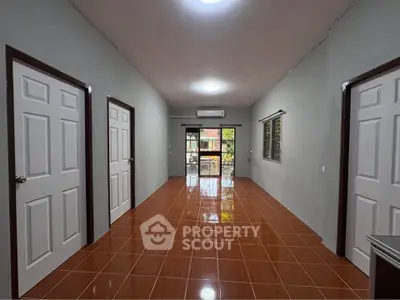 Spacious interior with tiled flooring and multiple doors, ideal for versatile living space.