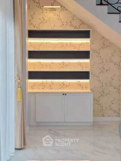 Elegant interior with illuminated shelves and floral wallpaper under staircase