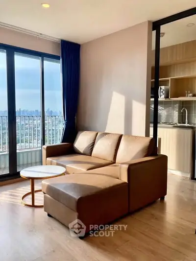 Modern living room with city view, featuring a cozy brown sofa and open kitchen layout.