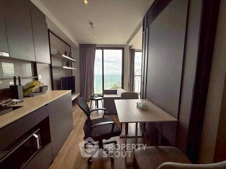 Modern living room with ocean view, sleek furniture, and open kitchen layout.