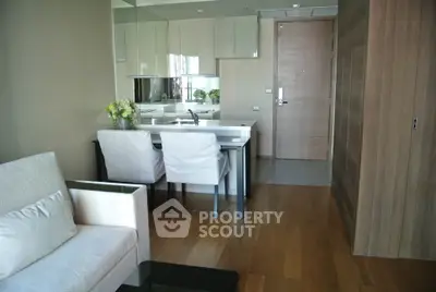 Modern apartment interior with open kitchen and cozy living area, featuring sleek furniture and wooden flooring.