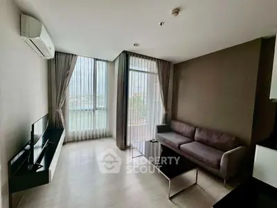 Modern living room with large windows and stylish furniture in a high-rise apartment.