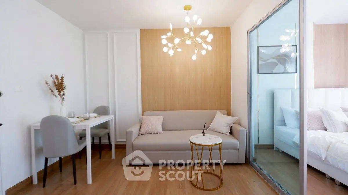 Modern living room with elegant chandelier and cozy sofa, adjacent to a stylish bedroom.