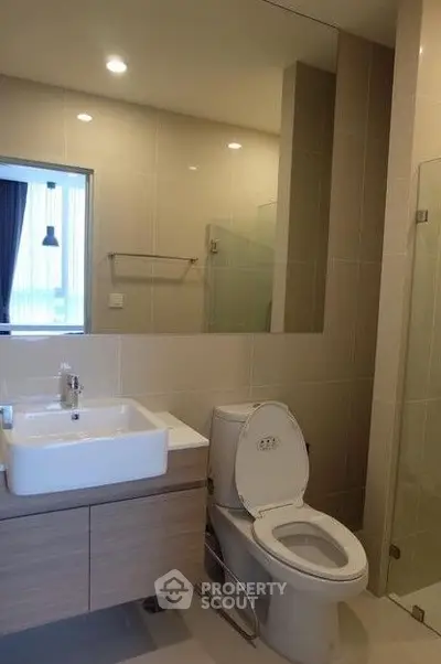 Modern bathroom with sleek fixtures and large mirror in contemporary apartment.