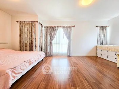 Spacious bedroom with elegant curtains and wooden flooring, perfect for a serene living experience.