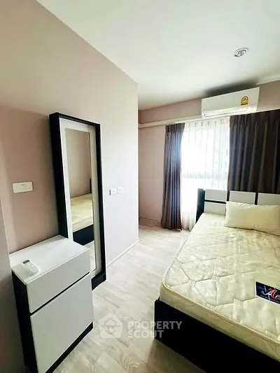 Modern bedroom with sleek furniture and natural light, featuring a stylish mirror and air conditioning.