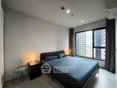 Modern bedroom with city view and sleek furnishings in high-rise apartment.