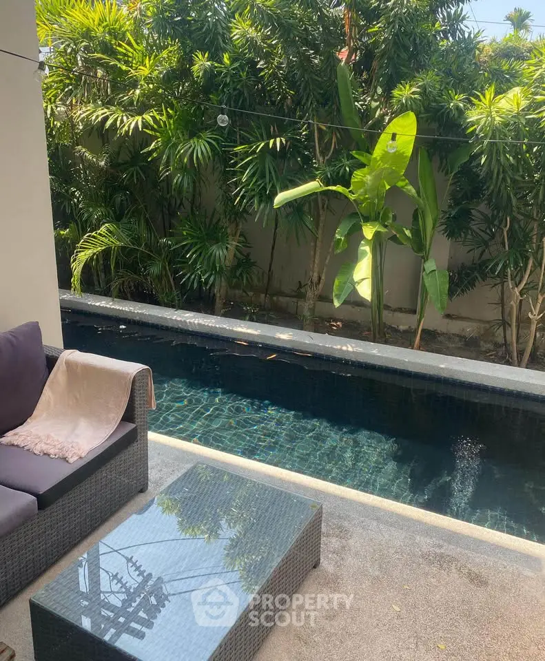 Luxurious outdoor pool area with lush greenery and cozy seating, perfect for relaxation and entertainment.