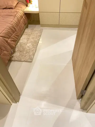 Cozy bedroom with beige tones and soft lighting, featuring a plush rug and modern design.