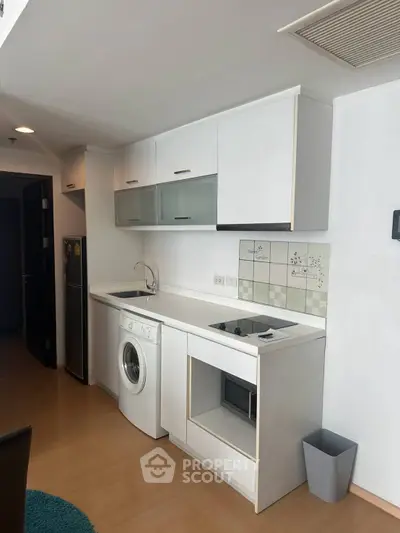 Modern compact kitchen with washing machine and electric stove in sleek apartment.