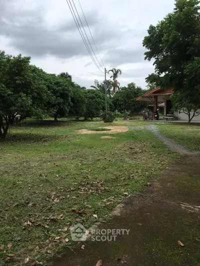 Spacious garden area with lush greenery and a charming house, perfect for nature lovers.