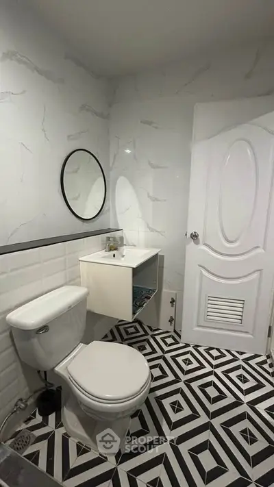 Modern bathroom with geometric floor tiles and sleek white fixtures.