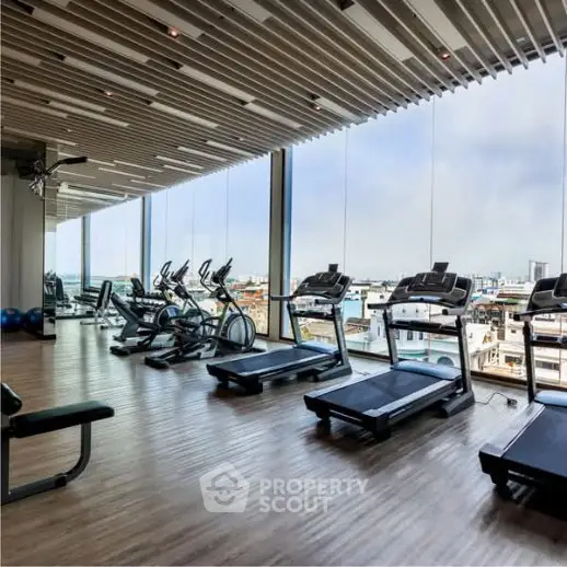 Modern gym with panoramic city views and state-of-the-art equipment in luxury building.