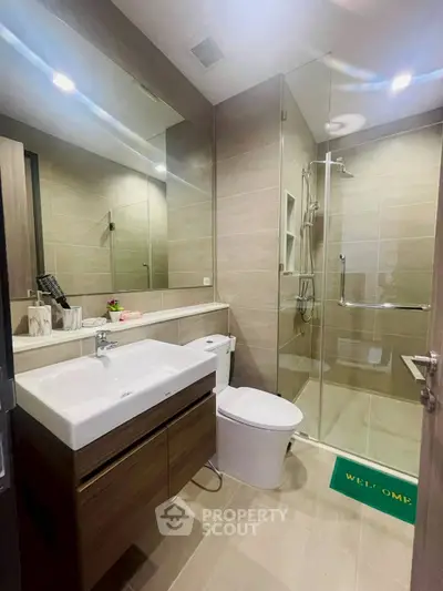 Modern bathroom with glass shower and sleek vanity in contemporary apartment.
