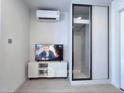 Modern living room with sleek TV setup and air conditioning in a stylish apartment.