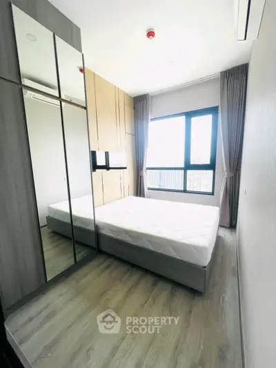 Modern bedroom with large window and mirrored wardrobe in a stylish apartment.