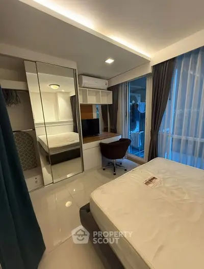 Modern bedroom with large windows, mirrored closet, and cozy workspace.