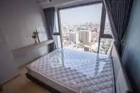 Spacious bedroom with stunning city view from large window, modern decor and natural light.