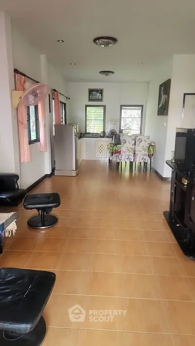 Spacious open-plan living room with kitchen, featuring tiled floors and modern furnishings.