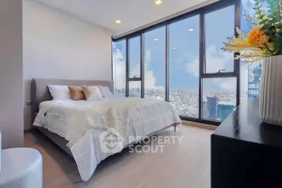 Luxurious bedroom with floor-to-ceiling windows offering stunning city views and modern decor.
