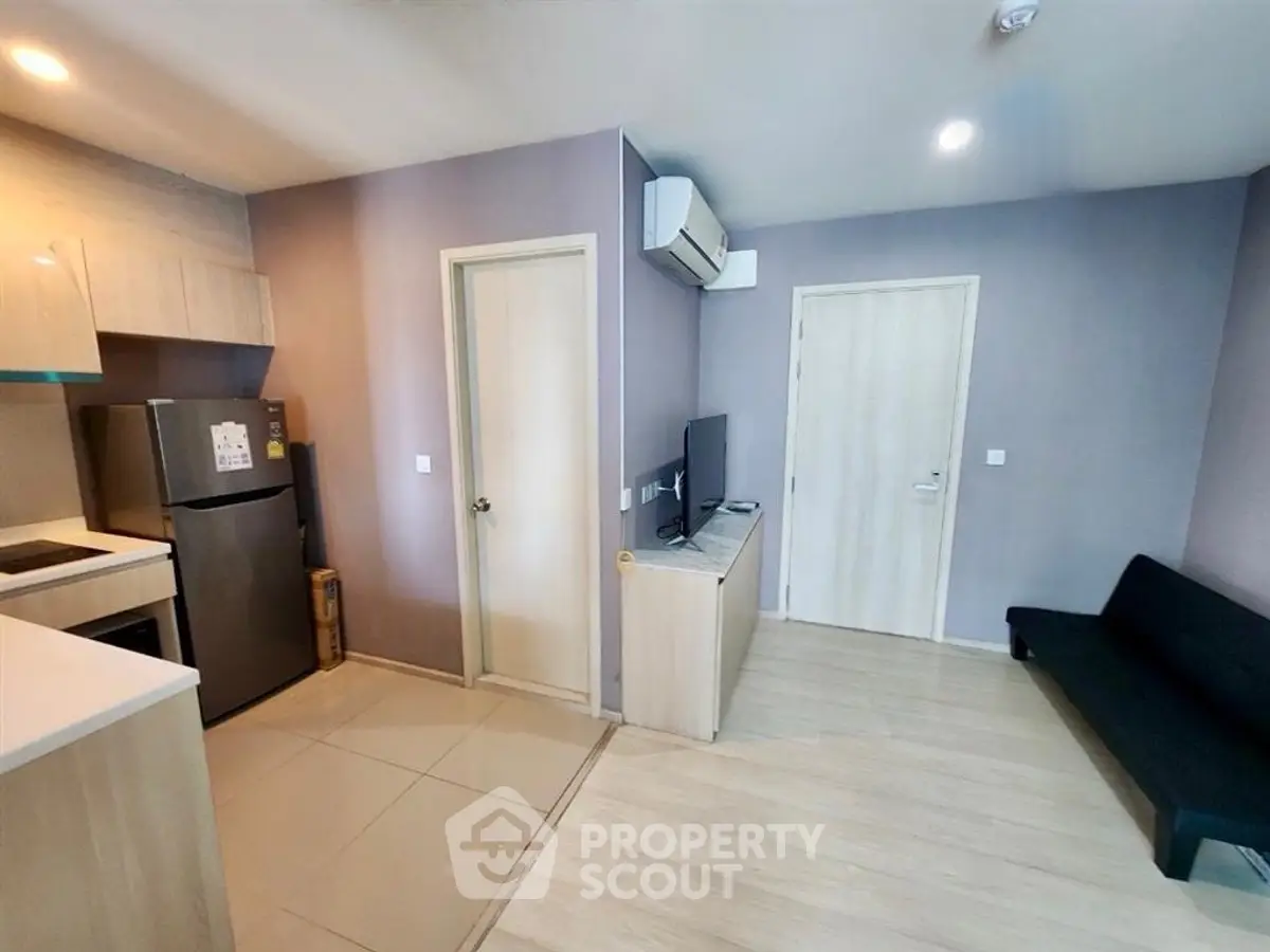 Modern apartment interior with compact kitchen and cozy living area, featuring sleek appliances and stylish decor.