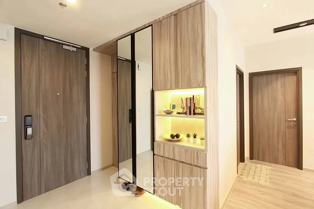 Modern apartment entrance with sleek wooden doors and stylish shelving unit.