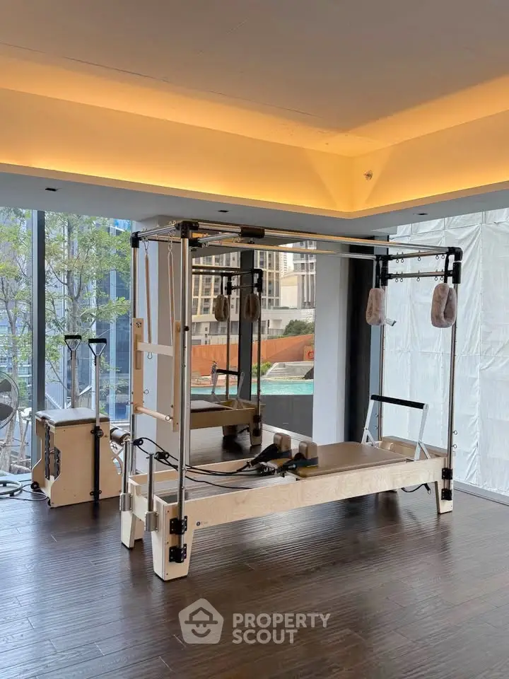 Modern gym with pilates equipment and city view, perfect for fitness enthusiasts.
