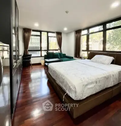Spacious bedroom with large windows and elegant wooden flooring