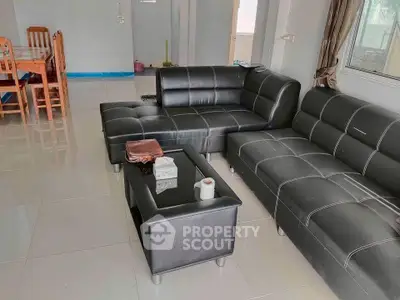 Spacious living room with modern black leather sofas and dining area in open layout.