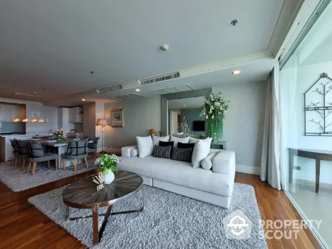 Spacious open-plan living area with plush seating, hardwood floors, and modern dining setup, perfect for entertaining and relaxation.