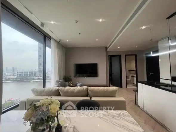 Luxurious living room with stunning river view and modern open kitchen layout.