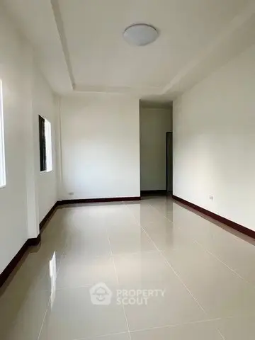 Spacious empty room with glossy tiled flooring and natural light