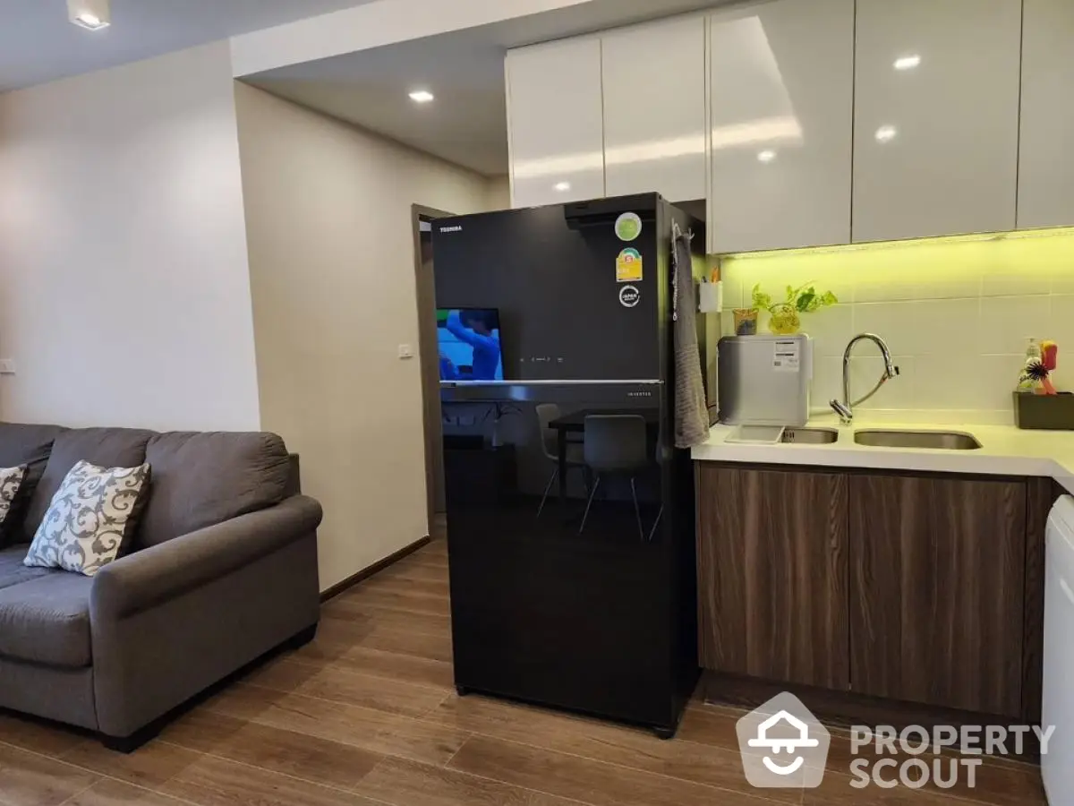 Modern kitchen with sleek black fridge and cozy living area