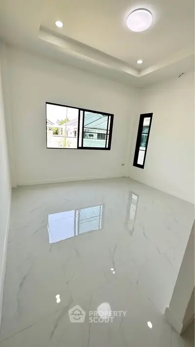 Spacious and bright room with glossy marble flooring and large windows offering natural light.