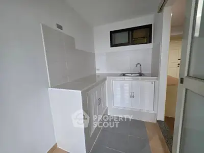 Compact kitchen with white cabinetry and tiled backsplash in modern apartment